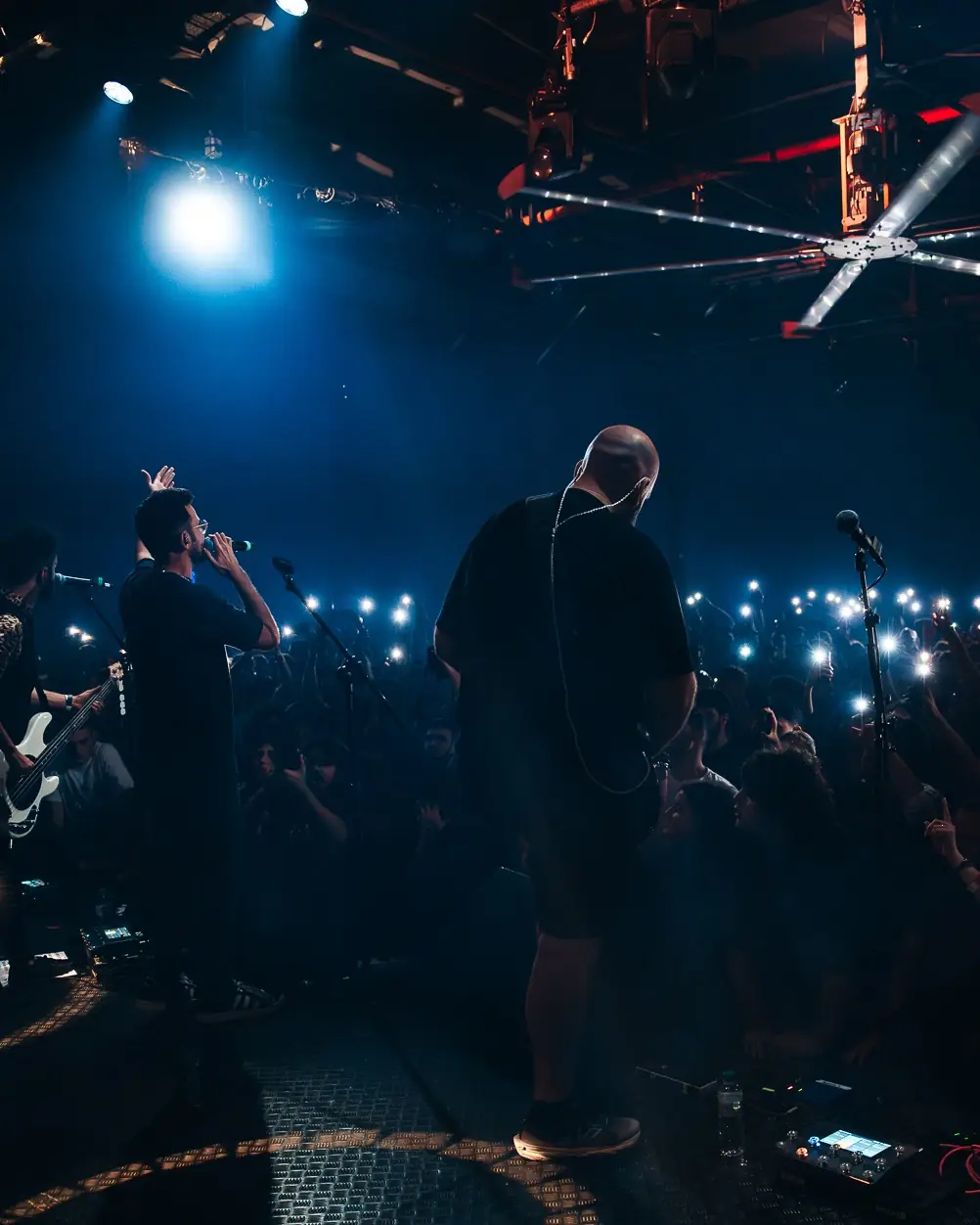 View from the back of the stage toward a crowd with phone lights