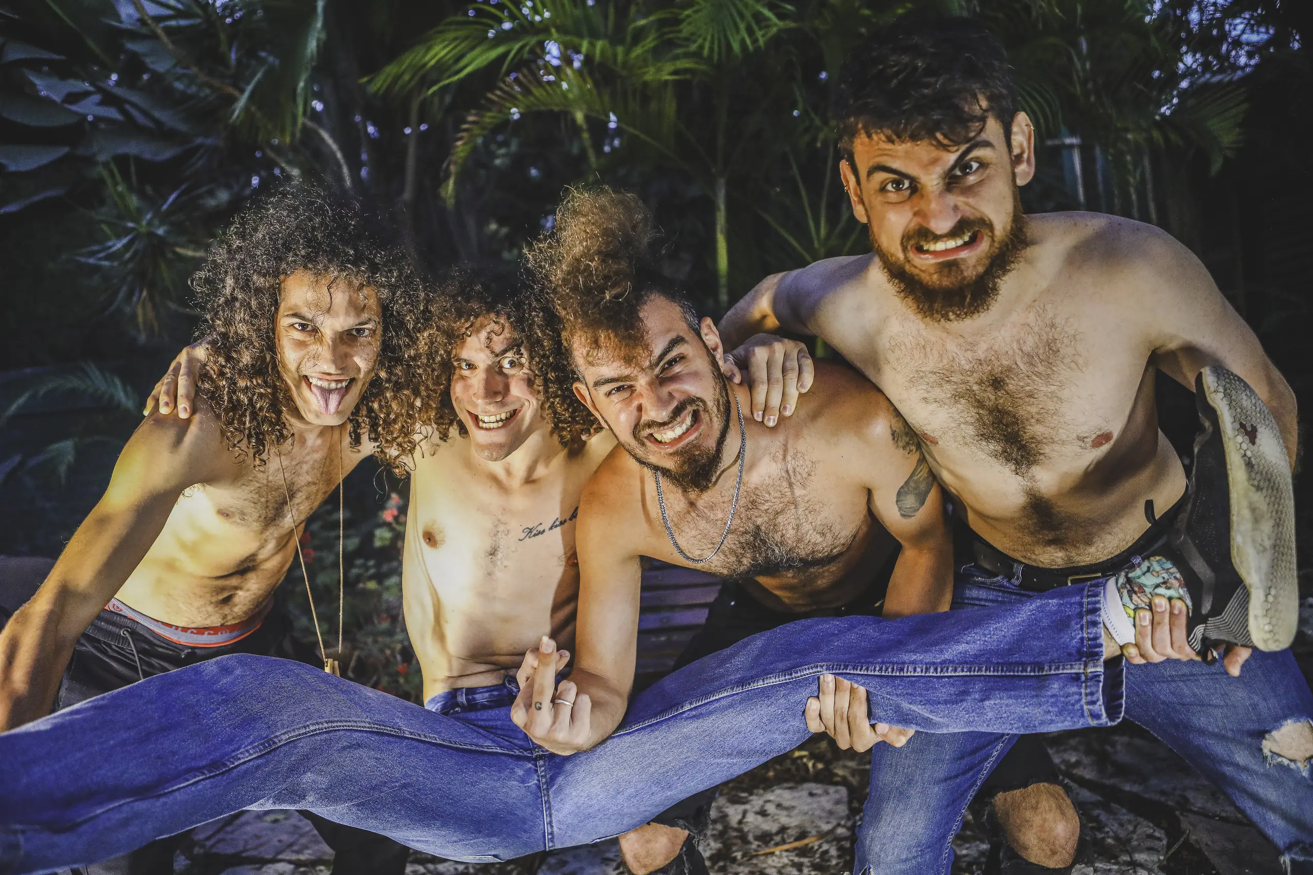 The four members of Dazy's Fasulia, shirtless in jeans, crammed together among tropical plants
