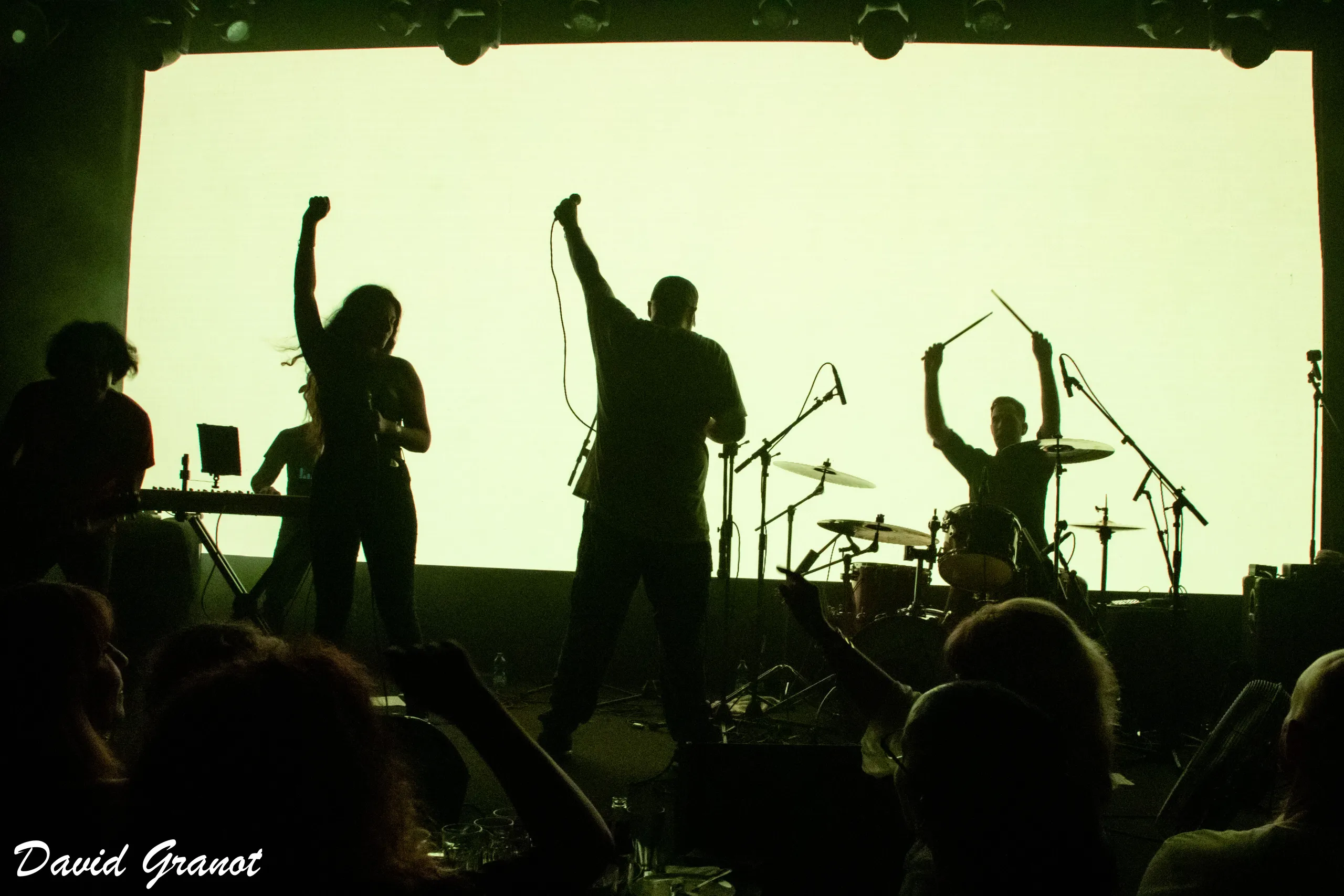 The band in silhouette against a lit screen, fists raised