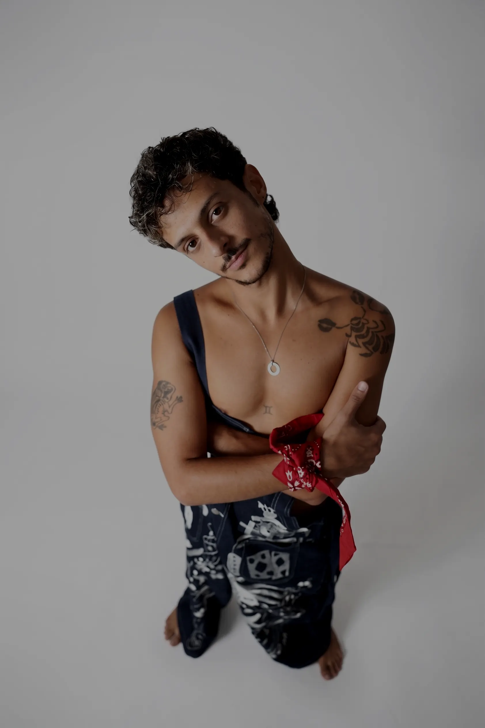 Yeled in the studio, arms crossed, a red bandana on his wrist